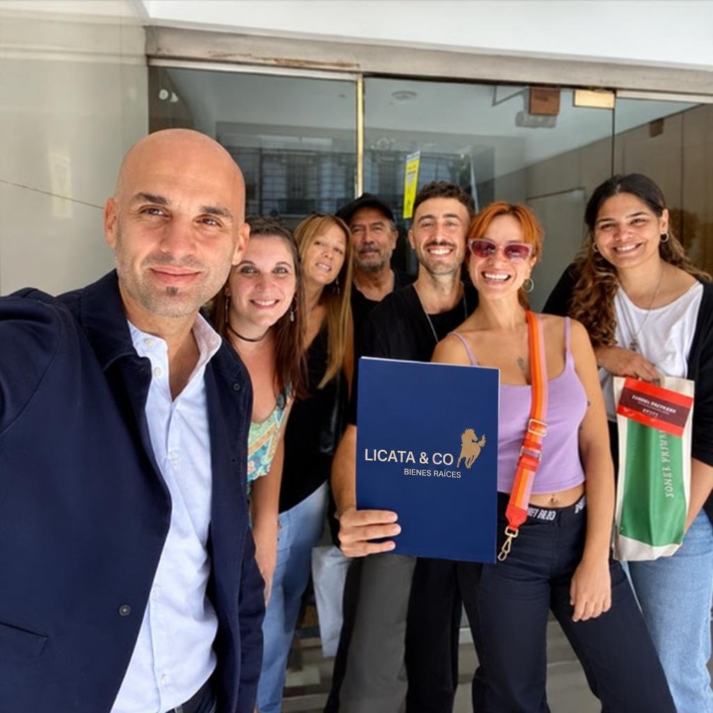 Juan Matías Licata junto a clientes de Licata & Co frente a una propiedad, con la carpeta de la inmobiliaria